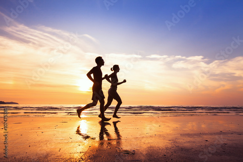 sport and healthy lifestyle, two people jogging at sunset on the beach