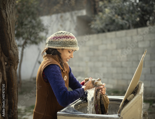 Woman in knit hat hand-washing clothing outdoors photo