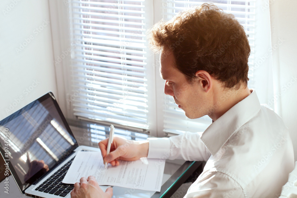 businessman working with documents, reading contract or filling tax form in the office near computer