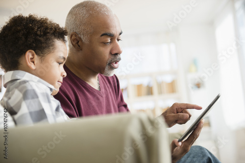 Mixed race grandfather and grandson using digital tablet