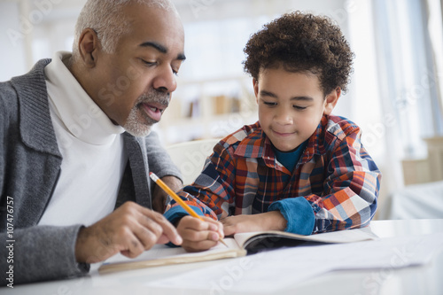 Mixed race grandfather helping grandson do homework photo