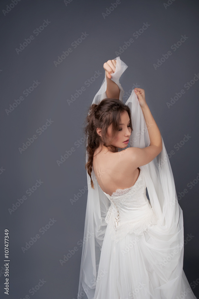 Fototapeta premium Bride in white wedding gown posing with veil