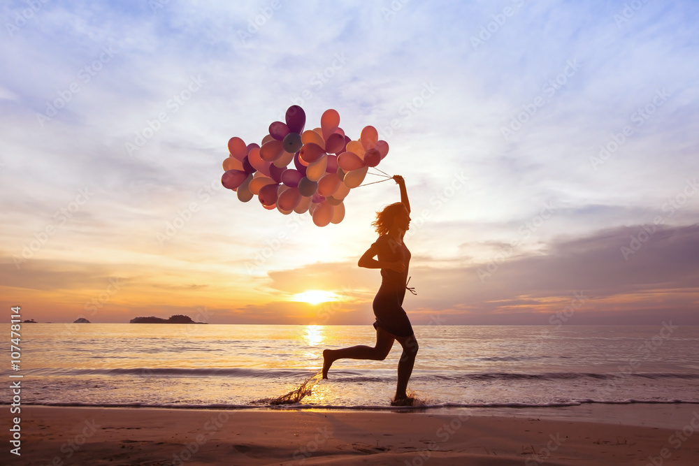 happiness concept, psychology of happy people, young woman running with multicolored balloons on the beach - obrazy, fototapety, plakaty 