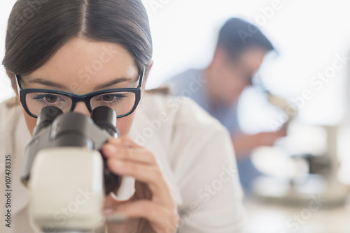 Young female scientist looking through microscope  photo