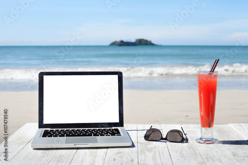office on the beach, laptop with empty screen, sunglasses and tropical cocktail © Song_about_summer