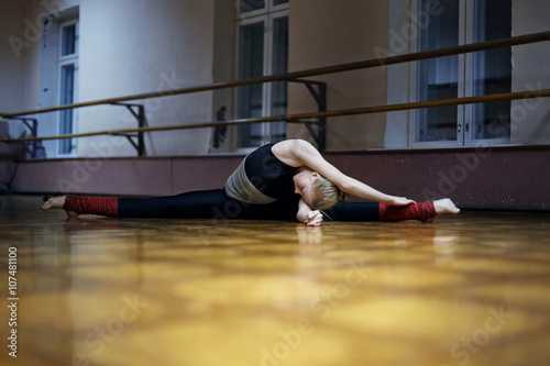Caucasian dancer stretching doing splits on studio floor photo