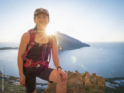 Japanese hiker standing on hilltop over ocean photo