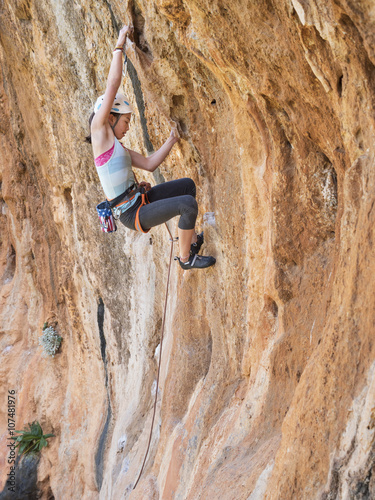 Mixed race girl climbing rock wall photo