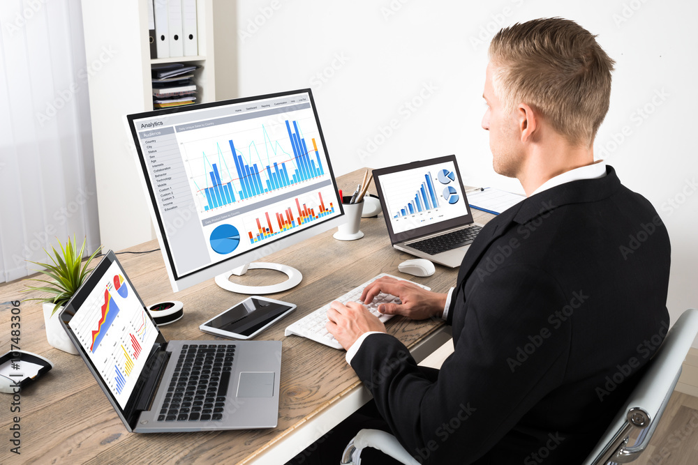 Businessman Analyzing Graphs In Office Businessman Analyzing Graphs In Office
