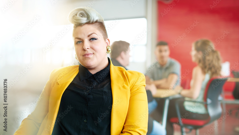 Confident and edgy female designer working on a digital tablet in red creative office space Confident and edgy female designer working on a digital tablet in red creative office space