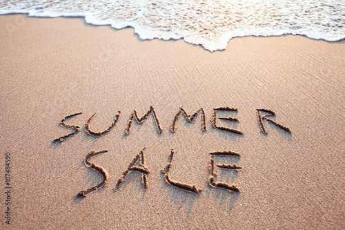 summer sale sign on the beach, text written on the sand