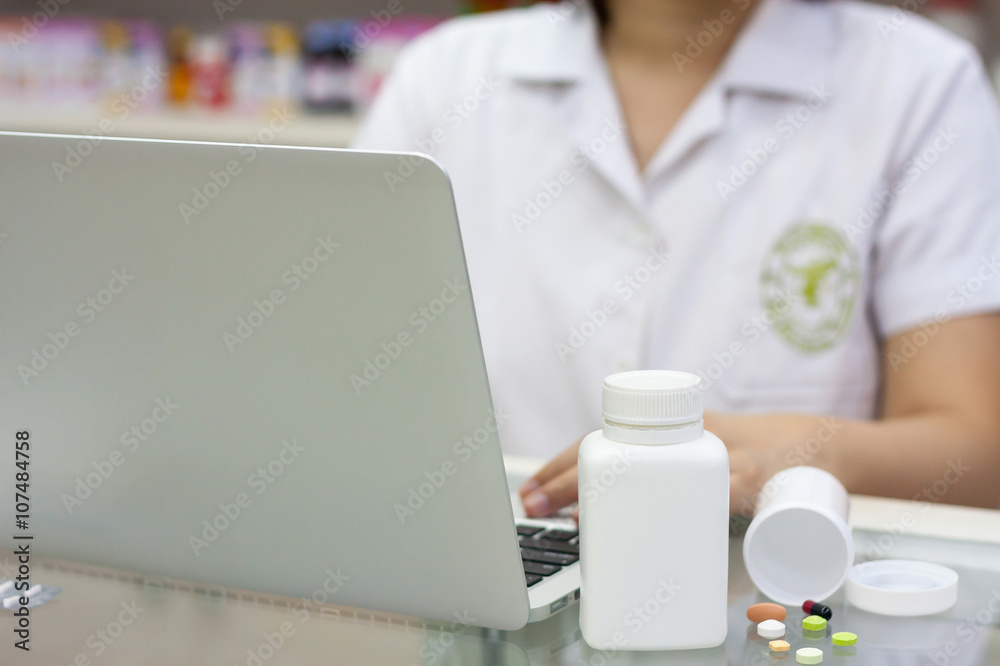 Pharmacist with laptop computer and medication in the pharmacy