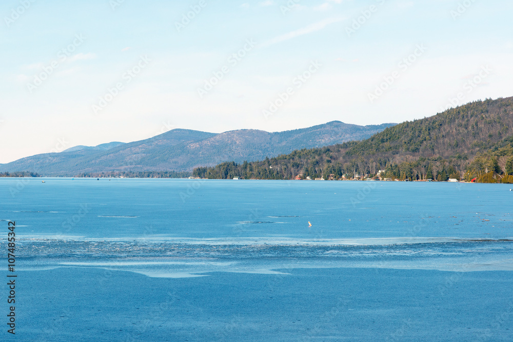 Color DSLR stock image of a frozen Lake George, with lake houses on the shore and Adirondack Mountains in background. Horizontal with copy space for text
