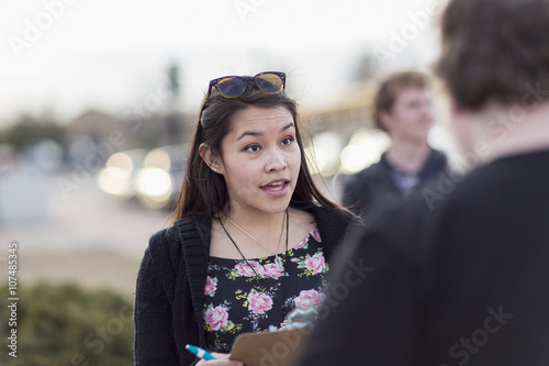 Canvasser with clipboard talking to man photo