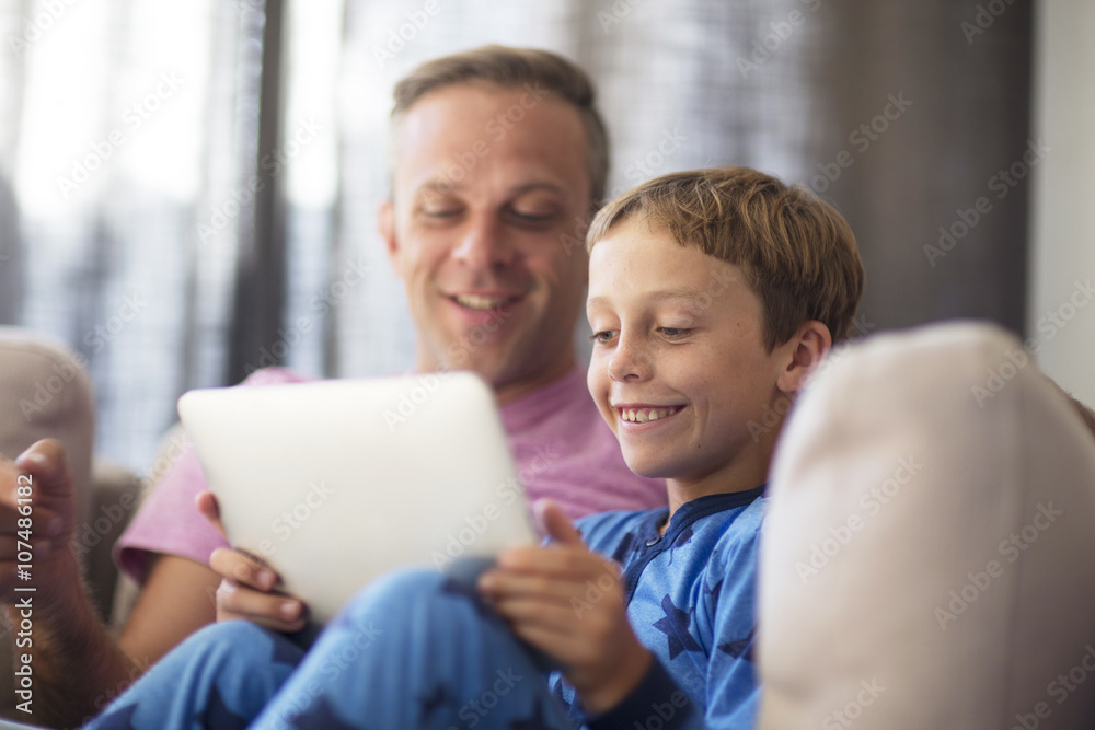 Caucasian father and son using digital tablet on sofa Caucasian father and son using digital tablet on sofa