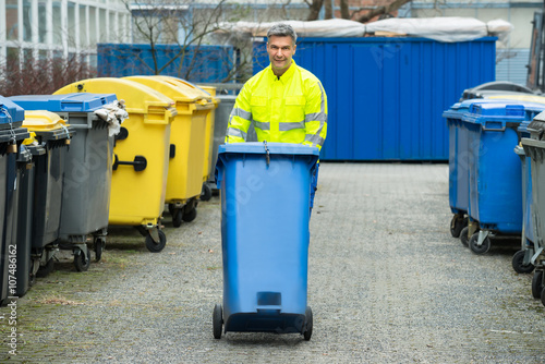 Male Worker Walking With Dustbin On Street