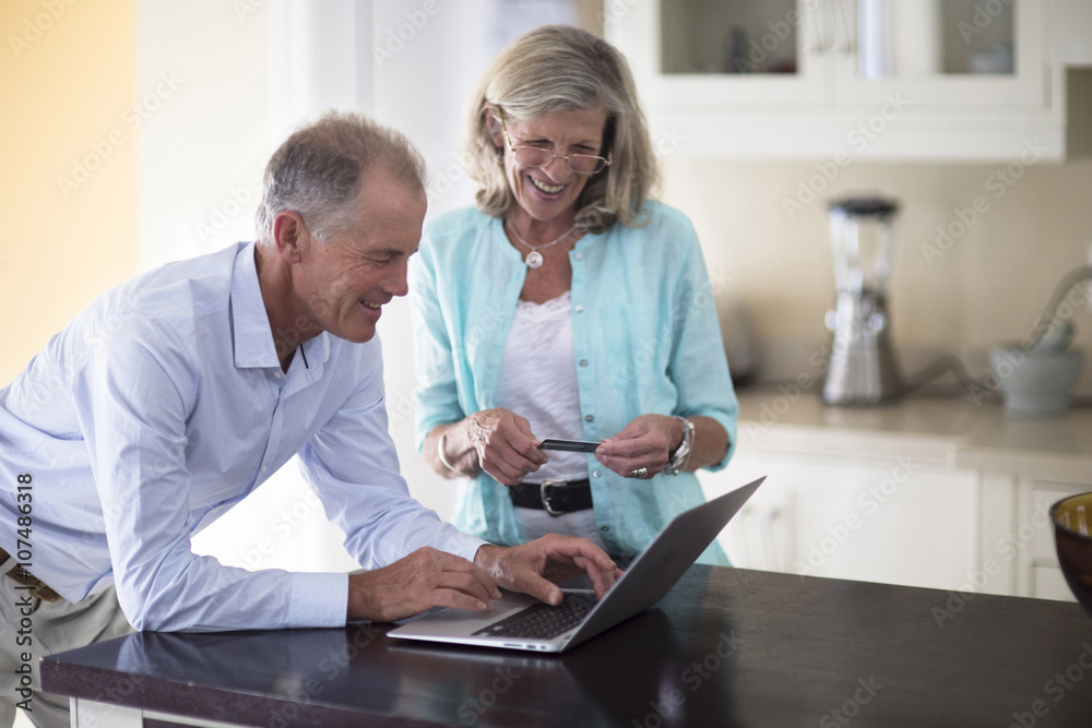 Caucasian couple using laptop on kitchen counter