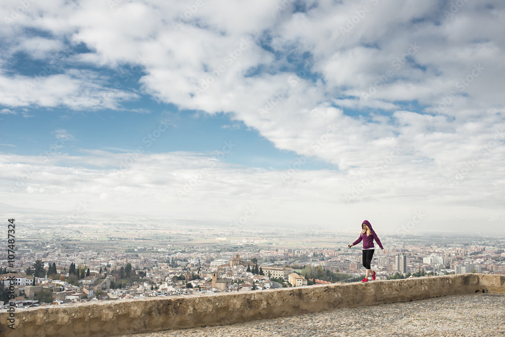 Caucasian woman on wall overlooking scenic view of cityscape, Granada, Spain Caucasian woman on wall overlooking scenic view of cityscape, Granada, Spain