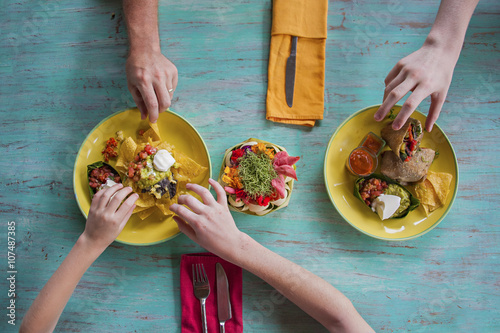 High angle view of hands reaching for food on plates