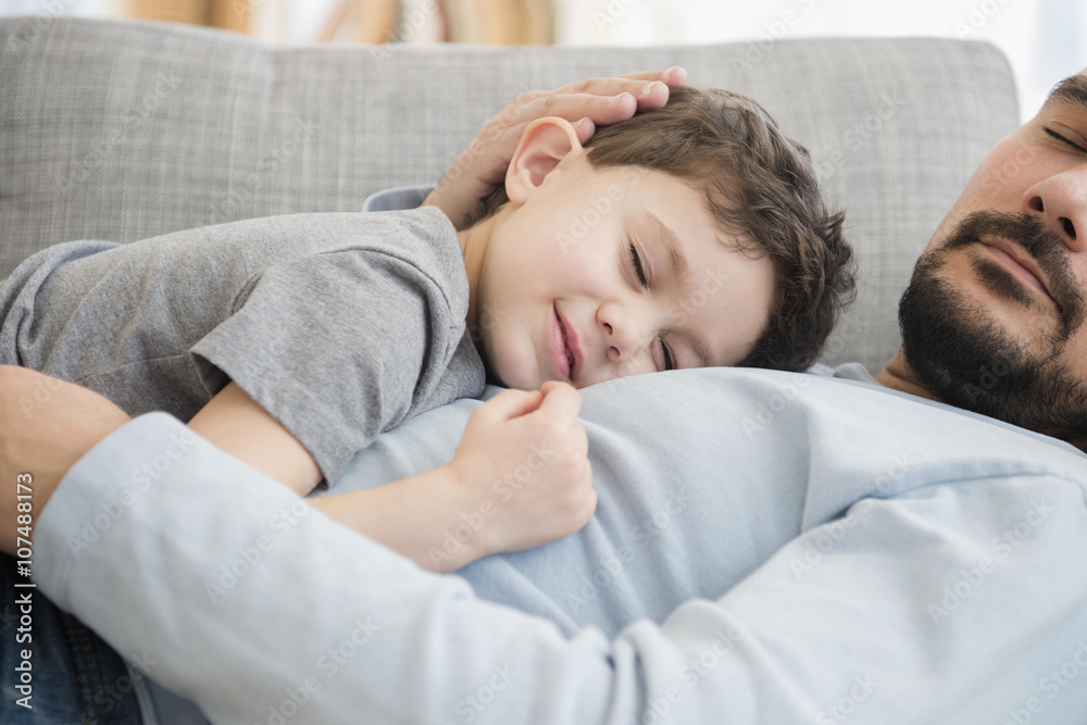 Caucasian father and son napping on sofa Caucasian father and son napping on sofa