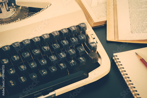 Old typewriter and old book on black table background vintage color