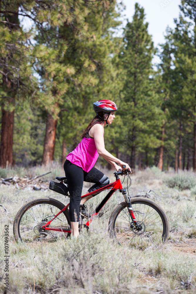 Woman riding mountain bike on trail in forest Woman riding mountain bike on trail in forest