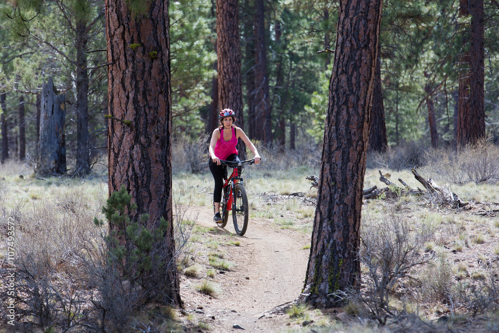 Woman riding mountain bike on trail in forest