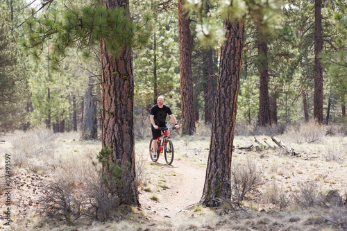 Bald man riding a mountain bike on a dirt trail in the forest © Mat Hayward