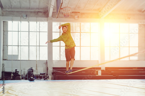 Bild auf Leinwand Man slacklining walking and balancing on a rope, slackline in a sports hall