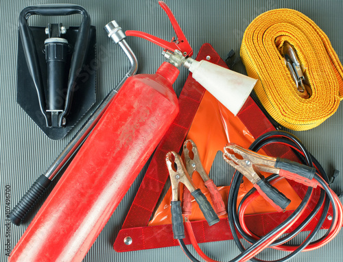 Elements of the essentials for a passenger car. Danger Safety Warning Triangle Sign, towing rope, fire extinguisher, Jumper cable, wheel wrench and shovel.