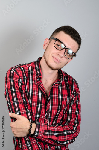 Portrait of young man smiling  with glasses on gray background © patramansky