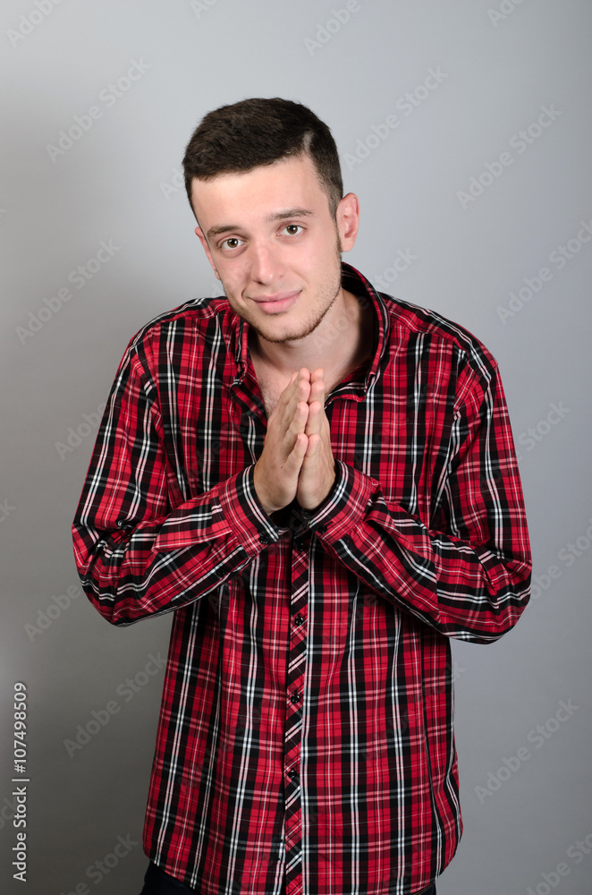 Fototapeta premium picture of a casual young man standing with his palms together