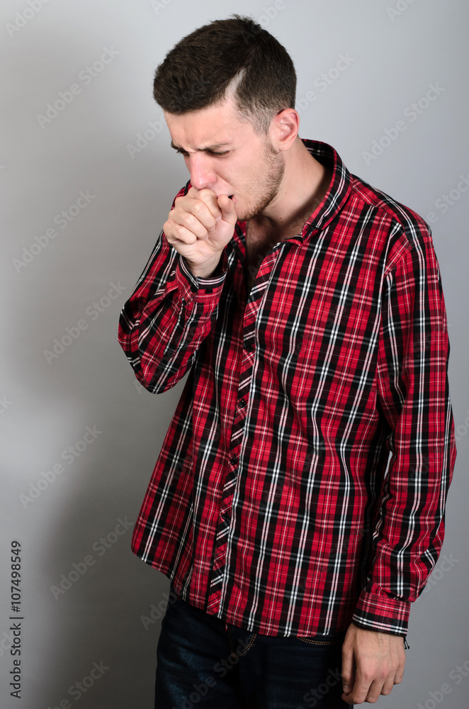 A man coughing into his fist. Gray background A man coughing into his fist. Gray background