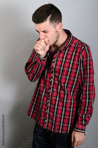A man coughing into his fist. Gray background