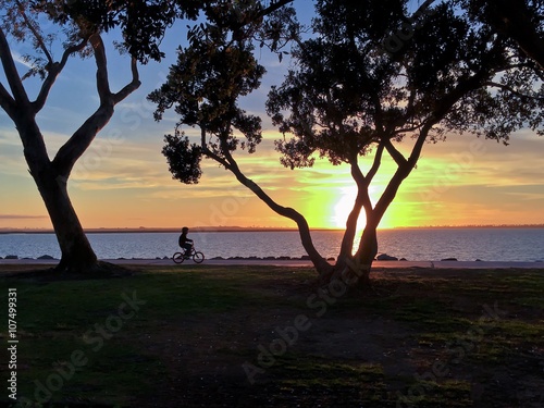  Sunset Silhouette of a child riding a bicyle along waterfront