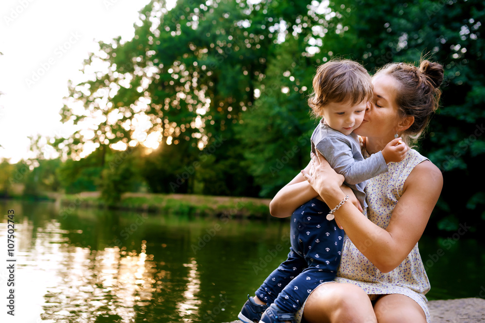 Young pregnant mother walking with her little son in summer park Young pregnant mother walking with her little son in summer park