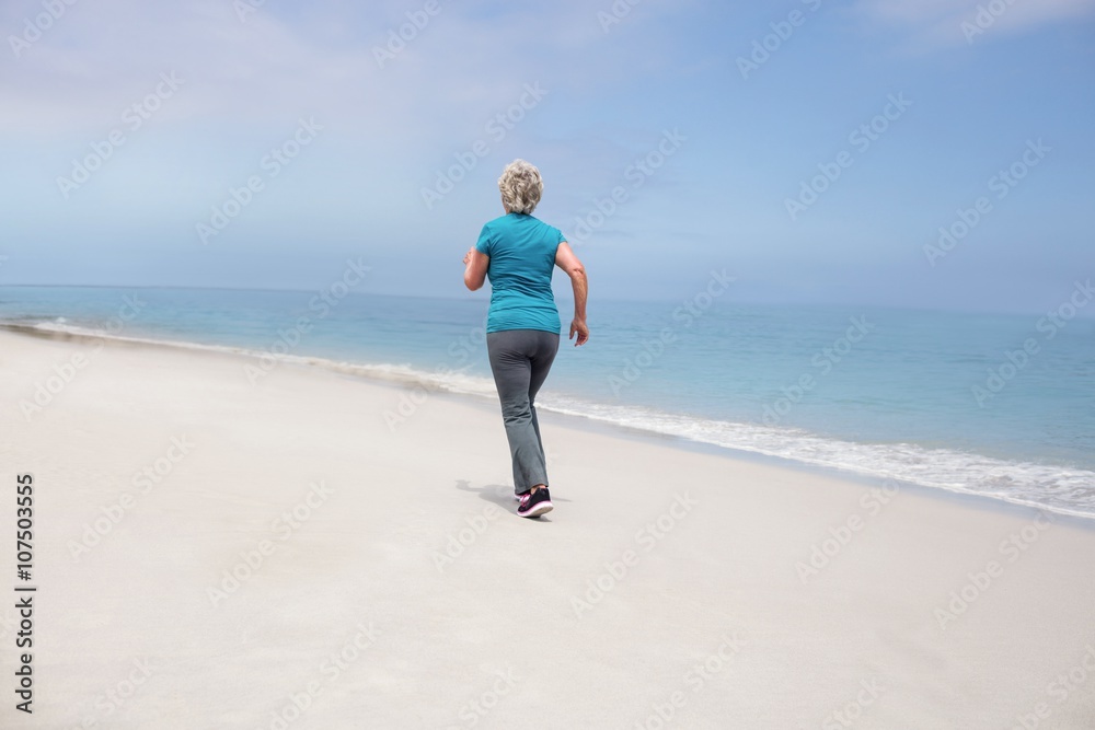 Rear view of senior woman jogging on the beach