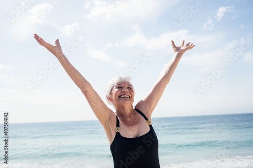 Excited senior woman standing on beach