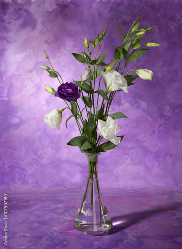 Bouquet of white and purple flowers ( eustoma) in a vase on abstract painting background. Still life