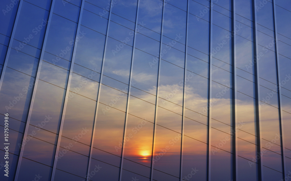 Fototapeta premium Reflection of sunset sky in metal wall of office building