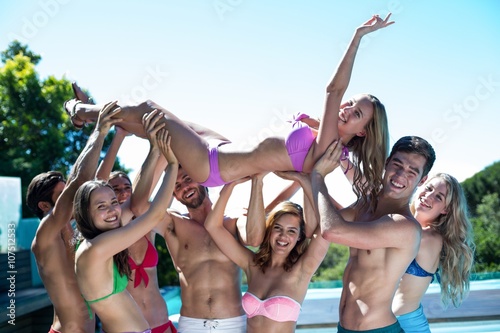 Group of friends lifting a woman near the pool