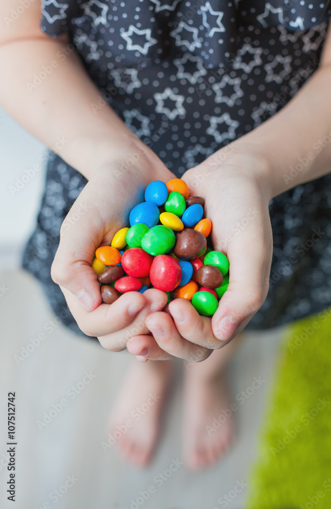 handful of colored candy in the hands of a little girl handful of colored candy in the hands of a little girl