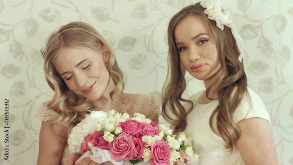 Two lovely girls posing with a big bouquet of roses in a box
