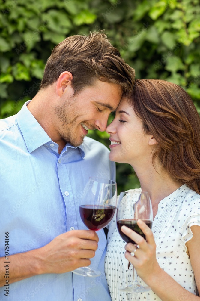 Couple holding wineglasses with eyes closed at front yard Couple holding wineglasses with eyes closed at front yard