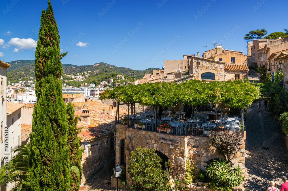 Sunny view of tower and terrace cafe in fortress Tossa de Mar, Girona province, Spain.