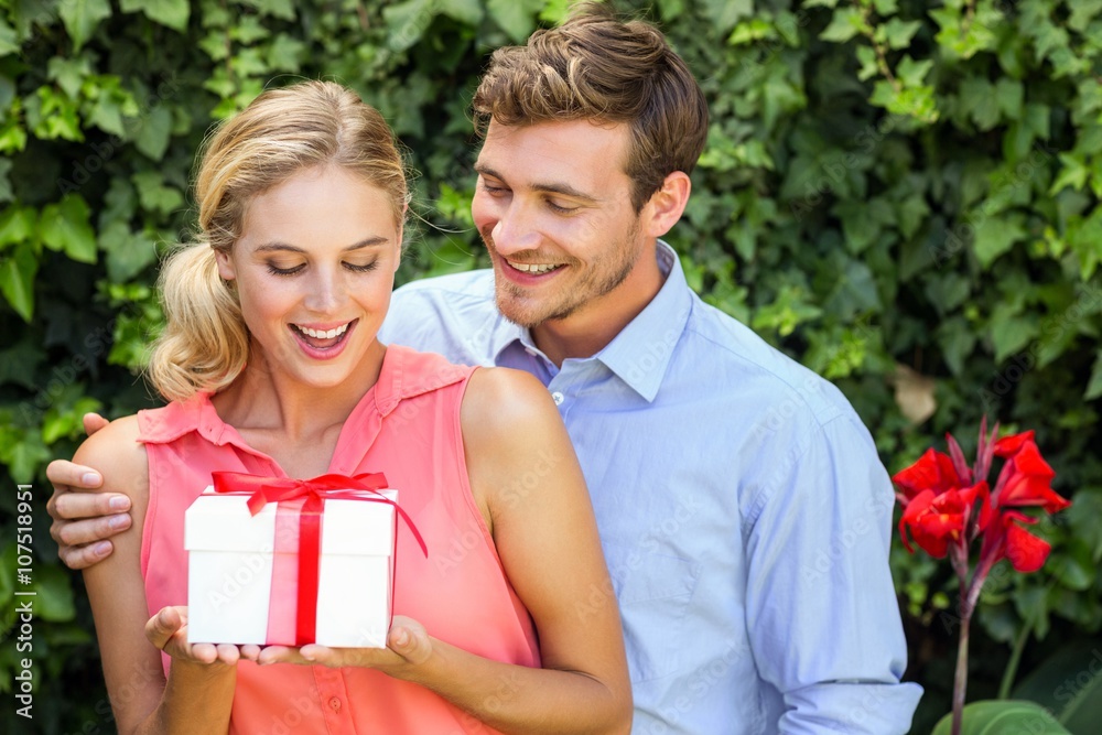 Man giving gift to surprised woman at front yard Man giving gift to surprised woman at front yard