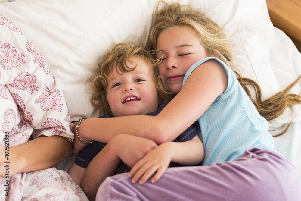 Caucasian brother and sister cuddling on bed Caucasian brother and sister cuddling on bed