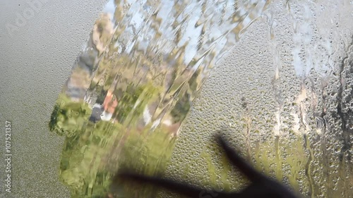 Une main nettoie la vitre embuée