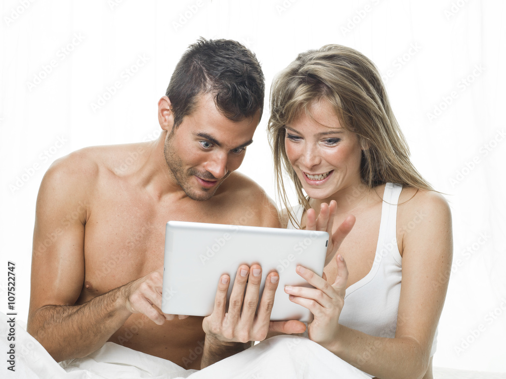 attractive couple watching things in a tablet attractive couple watching things in a tablet