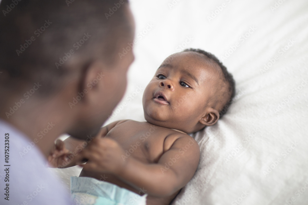 Close up of Black father playing with baby on bed Close up of Black father playing with baby on bed